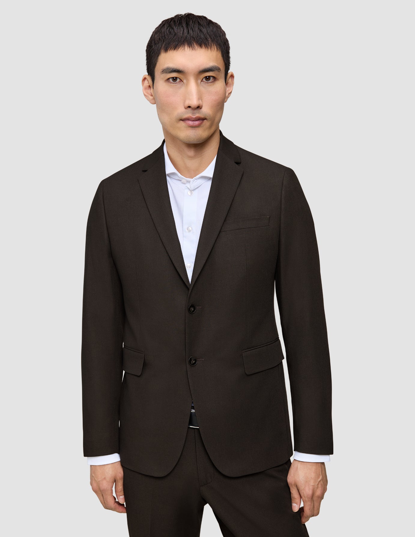 En mann kledd i en mørkebrun Motion Blazer Regular Cognac over en hvit skjorte med knapper.